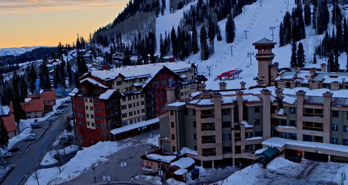This image captures snow-covered mountain ski slopes, pine forests, and ski lifts set against a serene sunset sky. The rustic lodge buildings nestled among the mountains evoke a sense of adventure and tranquility, perfectly illustrating the outdoor beauty surrounding Kendall 344.