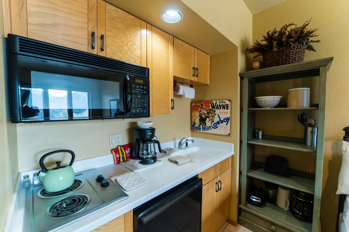 A warm and welcoming kitchen scene showing kitchen appliances, a decorative shelf, and wall art. The setting encourages socializing over coffee or preparing a quick meal, tying into the intimate and relaxed dining experience described in the section.