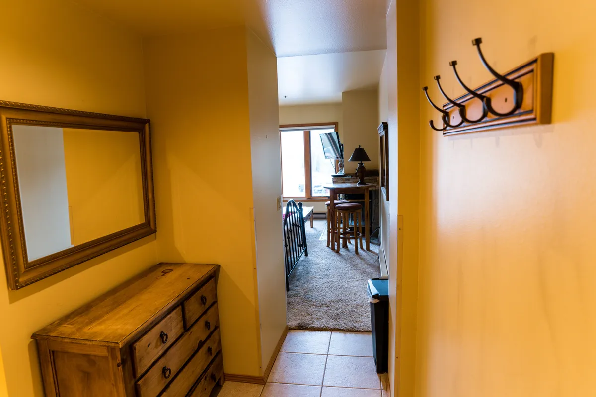 A cozy interior shows a mirror, chest of drawers, and a window letting in natural light. The scene is inviting, well-lit, and organized, making it an appealing spot for organizing belongings or simply enjoying a peaceful, light-filled moment.